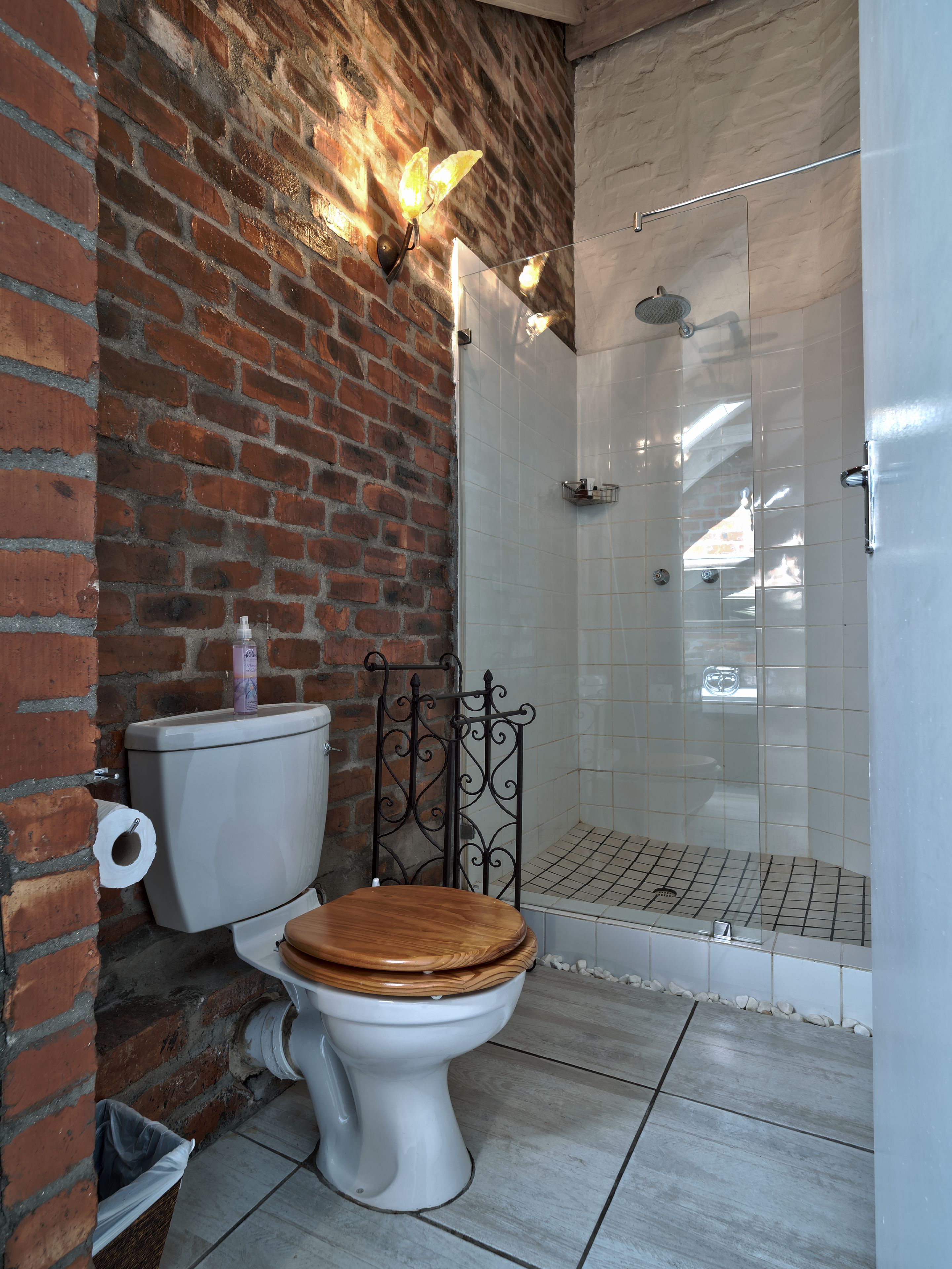 Ein Badezimmer mit Toilette, Dusche und einer Ziegelwand.