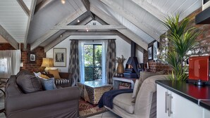 A cozy loft-style living area with a high ceiling, exposed beams, and a fireplace. There is a comfortable seating area with a sofa and a dining table.