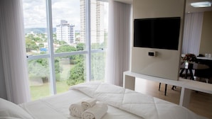 Camera d'hotel con un ampio letto, una TV a schermo piatto, una scrivania e vista sulla città.