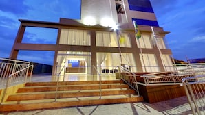 Un edificio moderno con una scala che conduce a un ingresso in vetro, ringhiere metalliche e una bandiera.