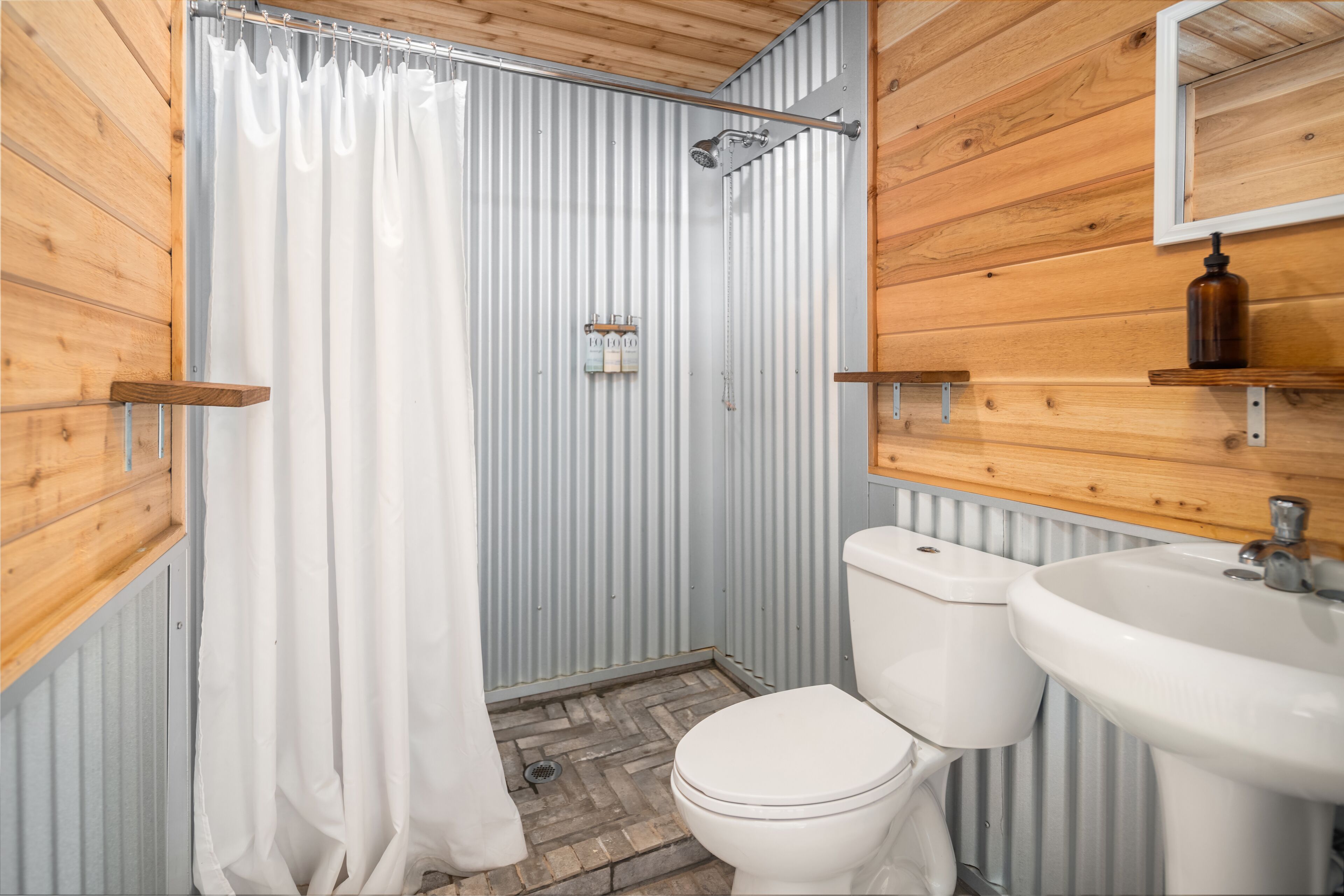 Une salle de bain avec douche, toilettes et lavabo.