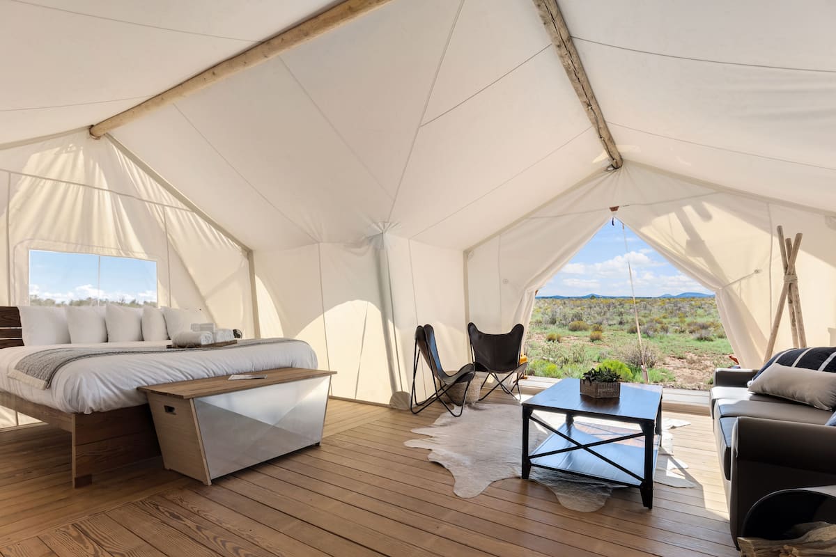 Un hébergement sous tente comprenant un lit, un coin salon et une vue sur le paysage désertique.