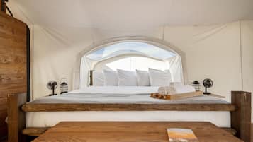 Una habitación con carpa, una cama, muebles de madera y vista al cielo.
