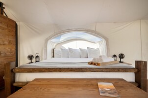 Una habitación con carpa, una cama, muebles de madera y vista al cielo.