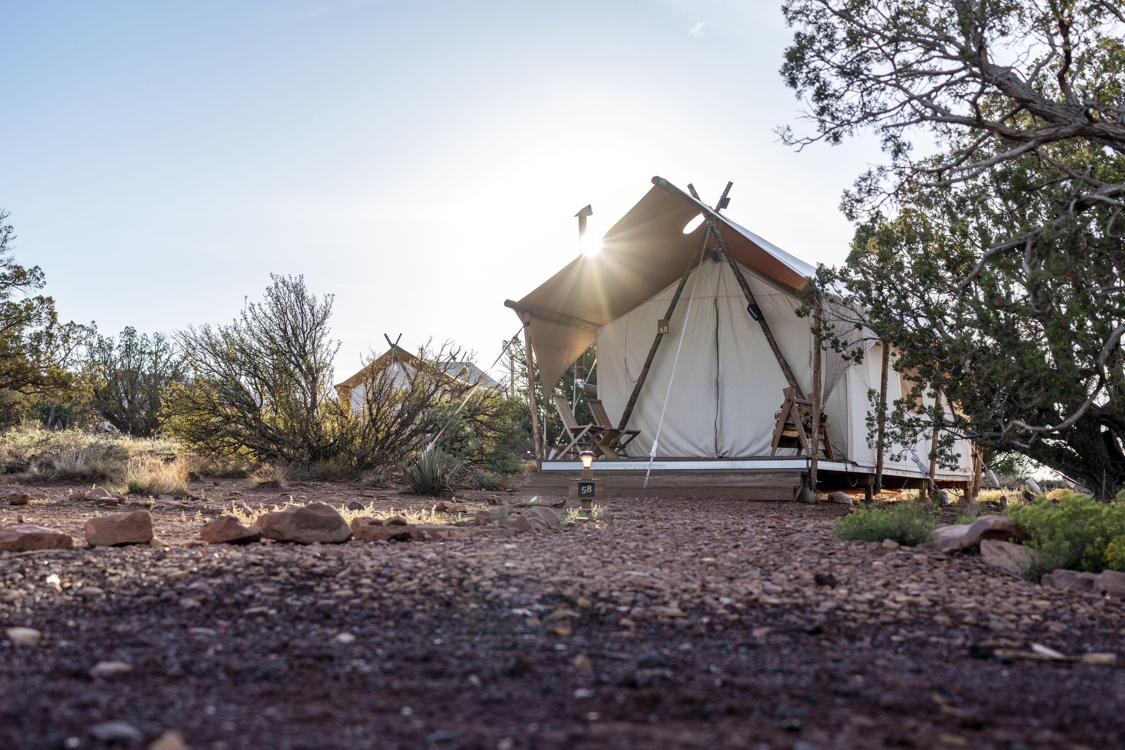 A tented accommodation with a clear view of the surrounding landscape, a ladder for access, and a sign indicating the number 58.