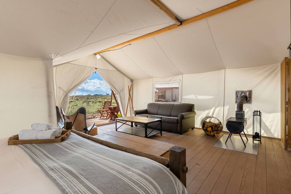 Une tente équipée d’un lit, d’un canapé, d’une petite table et d’une cheminée.