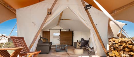 Une tente dotée d’un plancher en bois, d’un canapé, d’une table et d’une chaise.