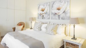 A bedroom with a large bed, two bedside tables with lamps, a chair, and a wardrobe.