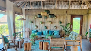 A cozy, rustic room with a wooden floor, a sofa with patterned cushions, and several potted plants.