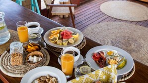 A breakfast table with plates of food, a coffee cup, and a view of the ocean.