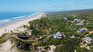 A coastal resort with thatched-roof cottages, a beach, and lush greenery.