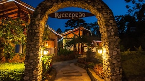 A stone archway with the word "Recepção" above a pathway leading to a building. - Pousada Cantinho das Estrelas (Camanducaia)