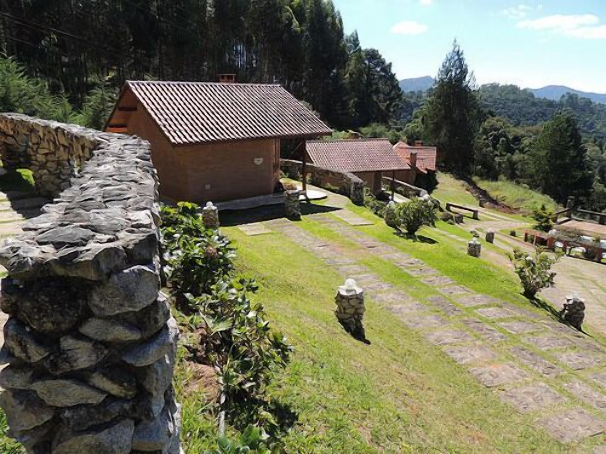 Un muro de piedra, un edificio pequeño con techo de tejas y un área ajardinada con senderos de piedra.