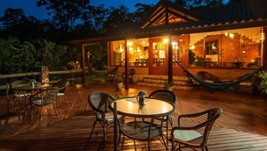 A wooden deck with outdoor seating and a hammock. - Pousada Cantinho das Estrelas (Camanducaia)