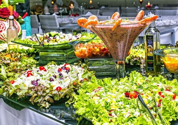 A buffet with various salads, a martini glass, and a bottle of olive oil.