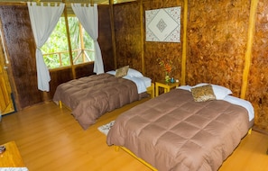 A room with two beds, wooden walls, and a window with curtains.