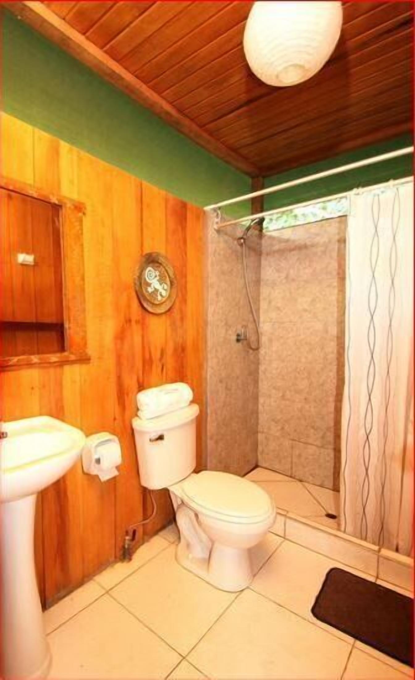 Un baño con paredes de madera, un inodoro, un lavabo y una ducha.