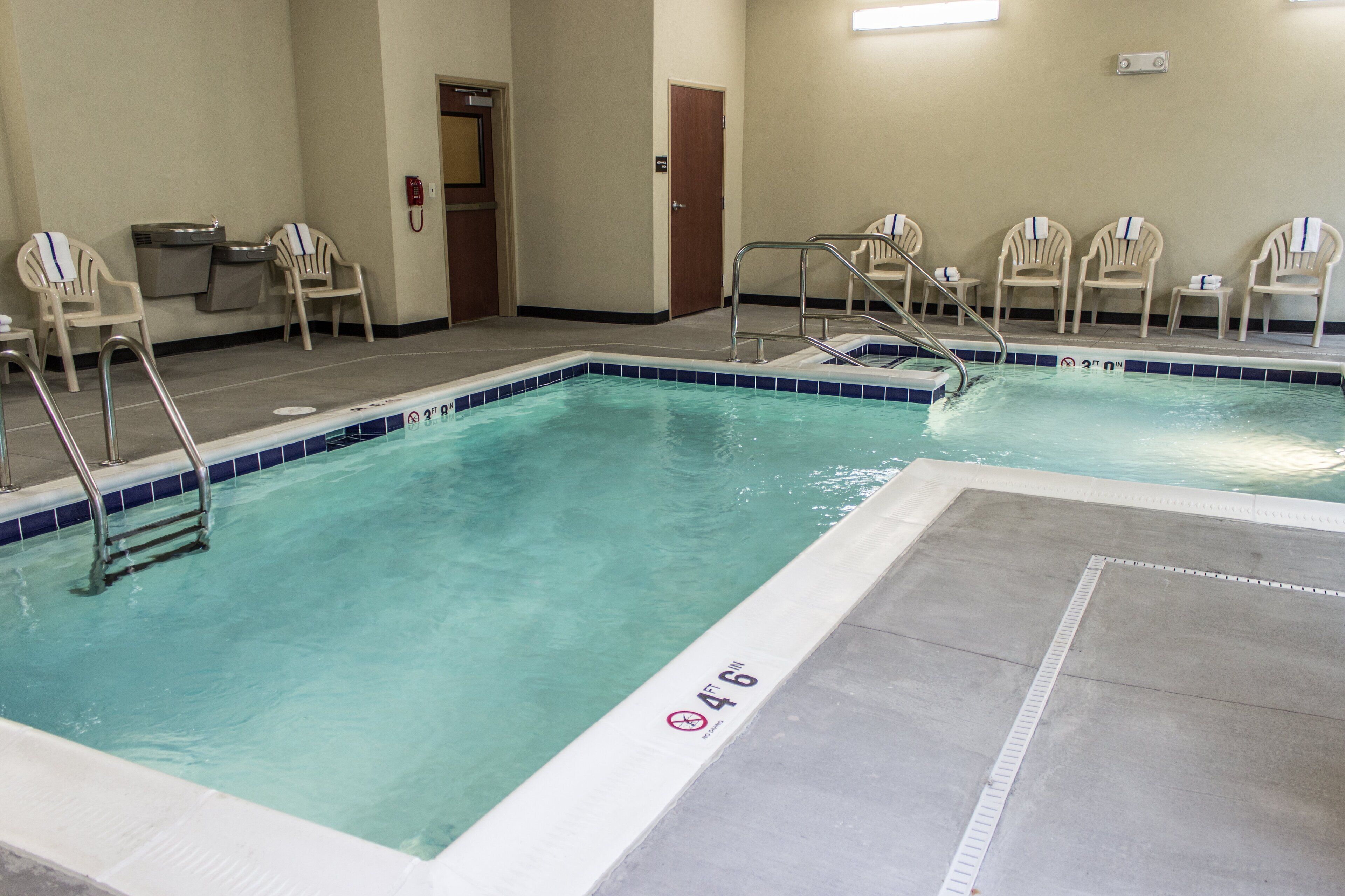 Une piscine intérieure à l’eau claire, avec un panneau indiquant qu’il est interdit de plonger et un indicateur de profondeur de 1,37 mètre (4 pieds 6 pouces).