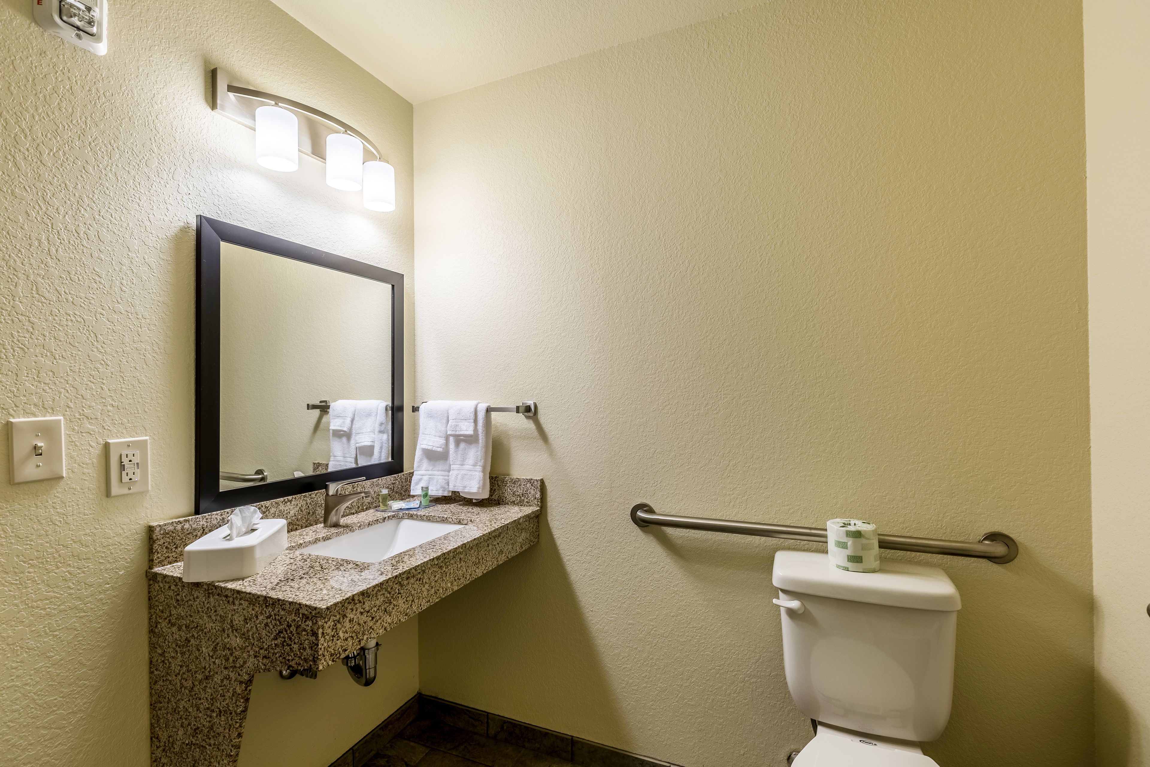 A bathroom with a sink, mirror, towel rack, and toilet.