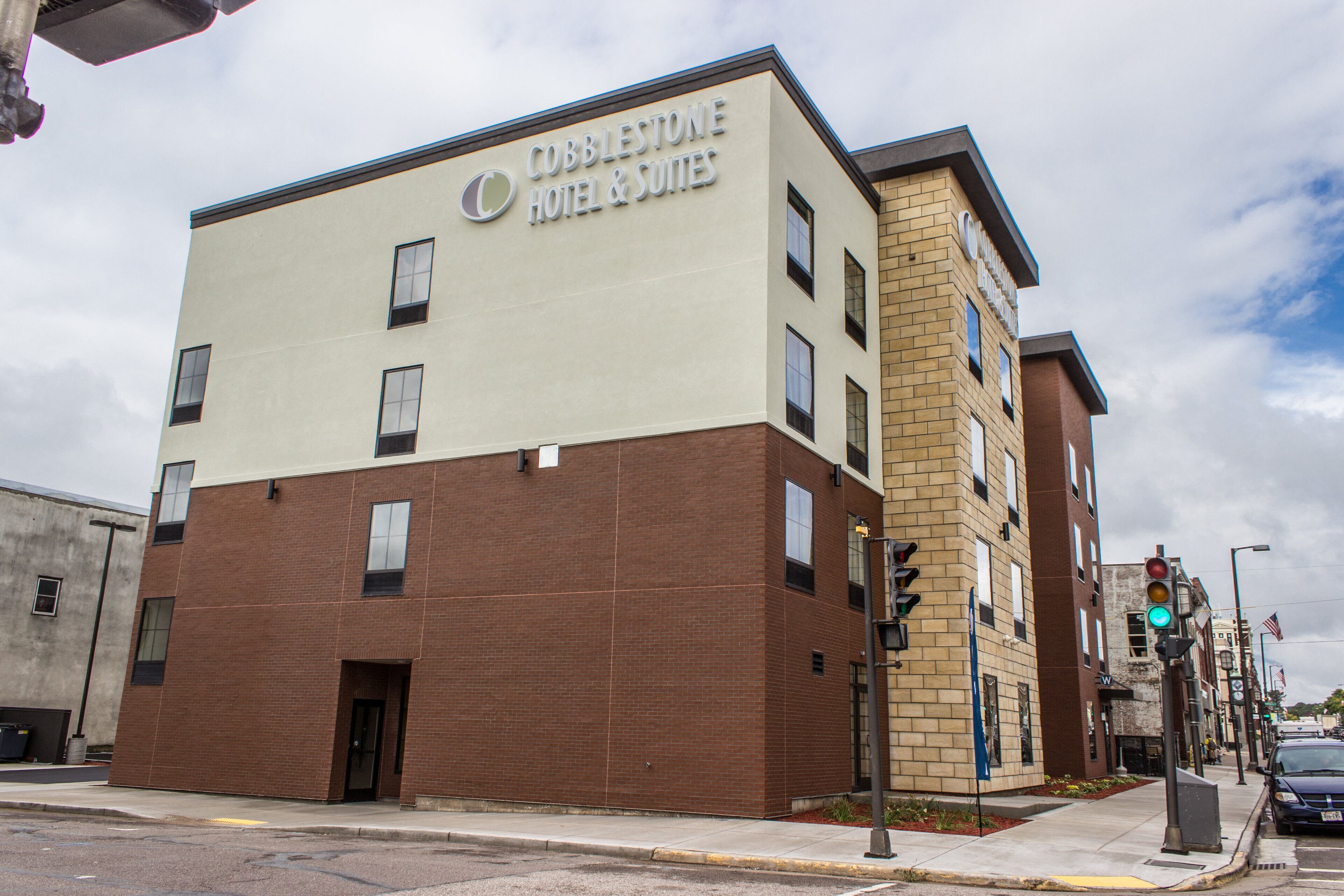 A two-story building with a sign reading "Cobblestone Hotel & Suites".