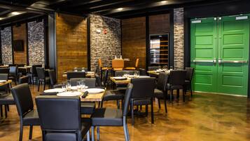 Un ristorante con diversi tavoli e sedie, una porta verde e un muro in pietra.
