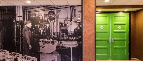 A corridor with a green door and a wall-mounted poster of industrial machinery.