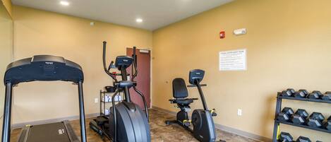 Un gimnasio con cintas de correr, elípticas y mancuernas.