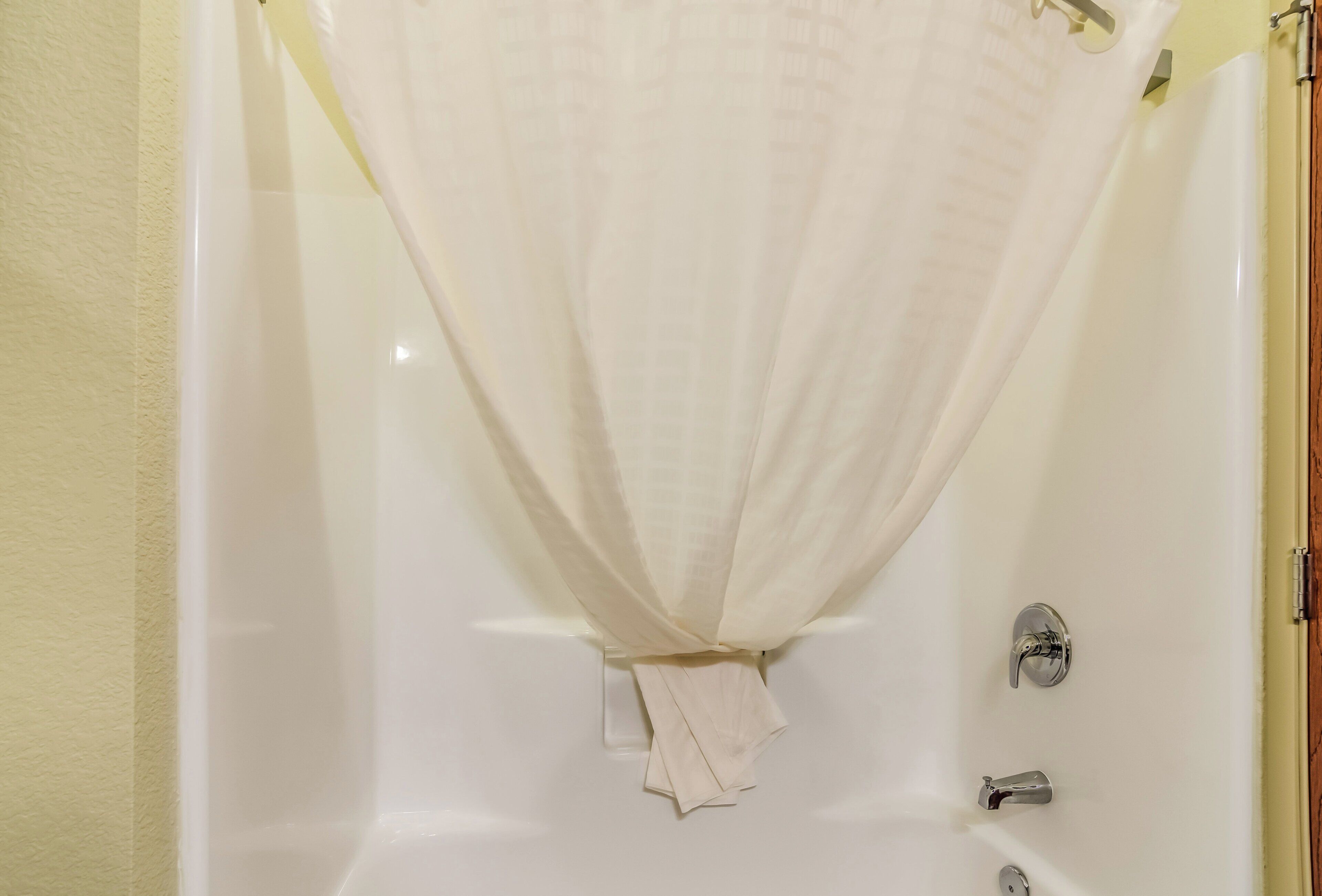 Una bañera blanca con una cortina de ducha atada en la parte inferior.