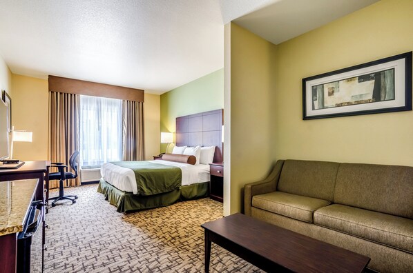 Une chambre d’hôtel avec un lit, un canapé, un bureau et une chaise.