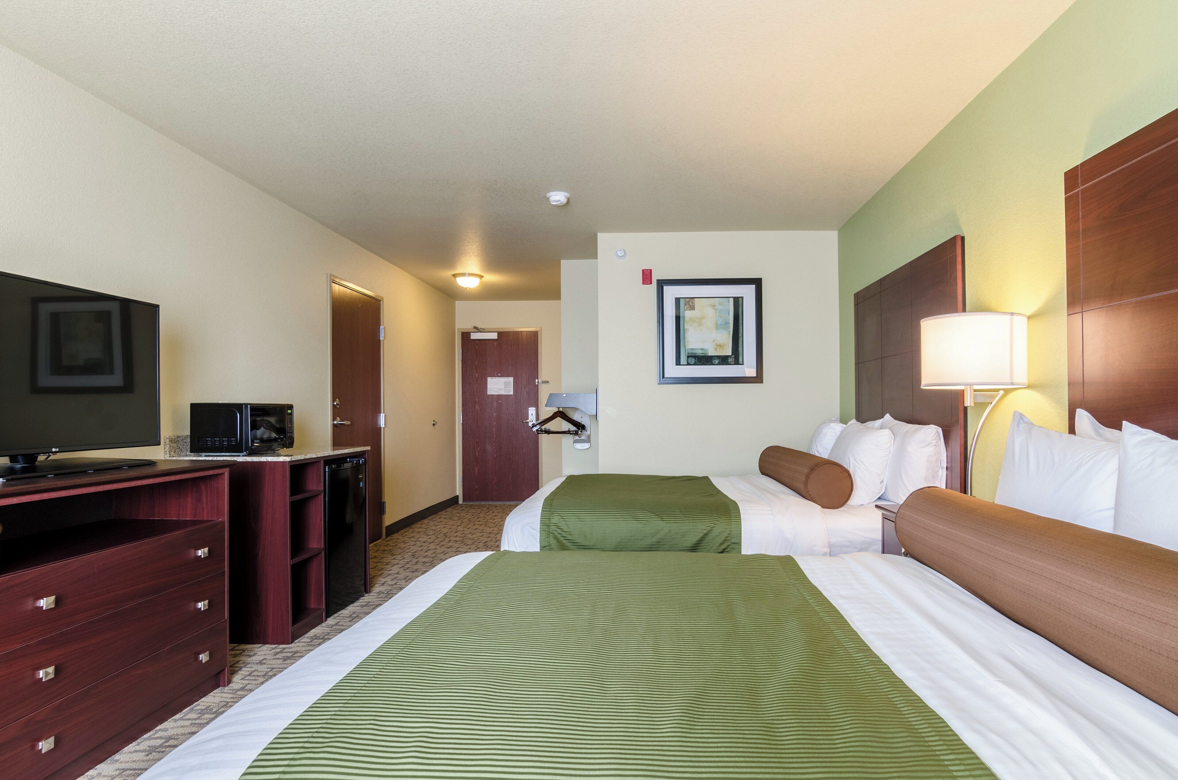 Une chambre d’hôtel équipée d’un lit, d’un bureau avec une télévision, d’un four à micro-ondes et d’un porte-manteau.
