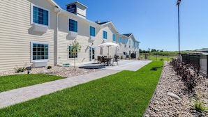 A hotel with a patio area, outdoor seating, and a clear blue sky.