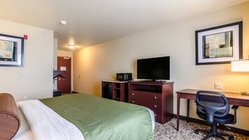 A hotel room with a bed, desk, chair, television, and a microwave.