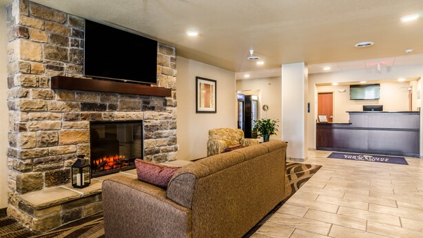 A modern lobby with a stone fireplace, a comfortable seating area, a reception desk, and a flat-screen TV mounted on the wall.