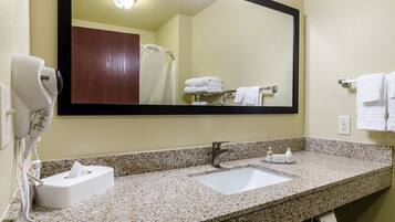 A bathroom with a granite countertop, a white sink, a mirror, a towel rack, and a hairdryer.