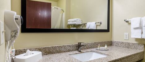 A bathroom with a granite countertop, a white sink, a mirror, a towel rack, and a hairdryer.
