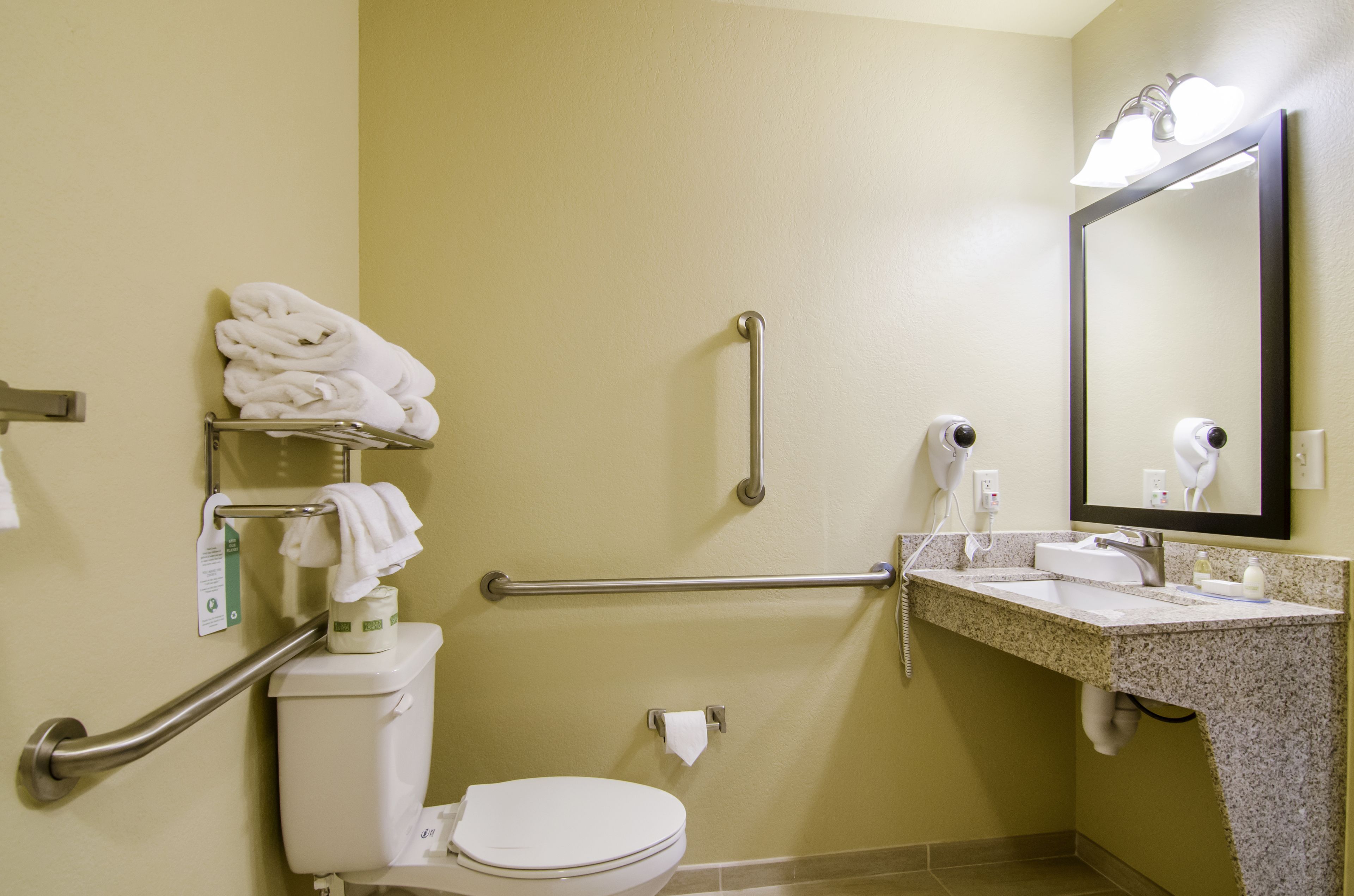 A bathroom with a toilet, a sink, a mirror, and a towel rack.