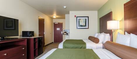 A hotel room with a bed, a desk with a television, a microwave, and a coat rack.