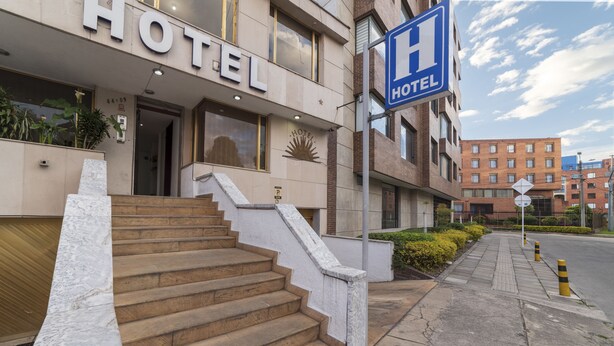 A hotel entrance with a staircase leading to the door, a 'HOTEL' sign above the entrance, and a 'P' parking sign nearby. - Hotel Central Park (Bogotá)