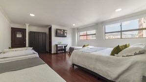 Habitación de hotel con dos camas, un escritorio, un televisor y vistas a la ciudad.