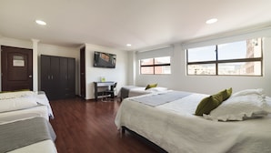 A hotel room with two beds, a desk, a TV, and large windows. - Hotel Central Park (Bogotá)