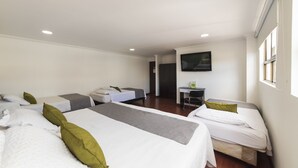 A hotel room with two beds, a desk, and a TV. - Hotel Central Park (Bogotá)