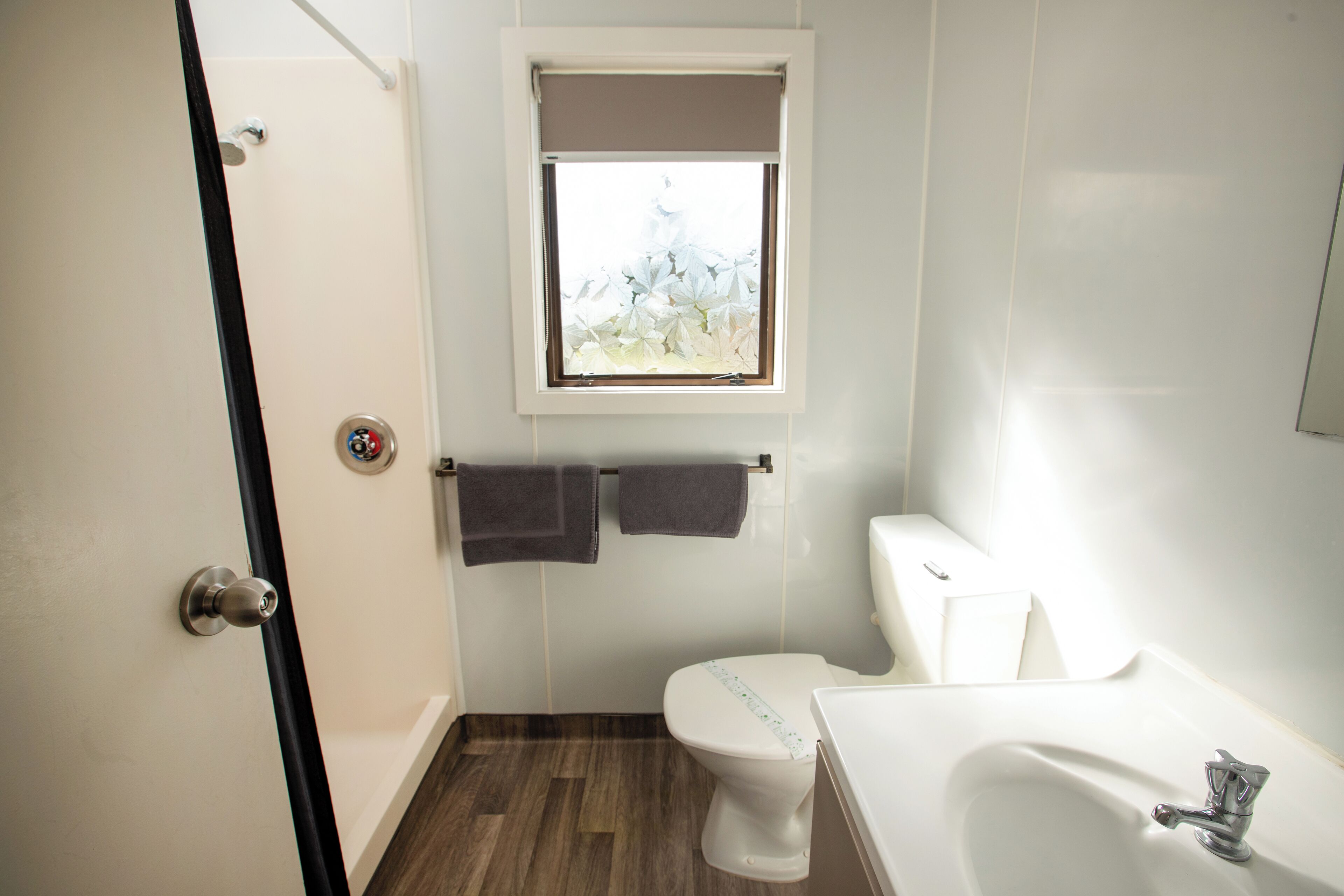 A bathroom with a toilet, sink, and window.
