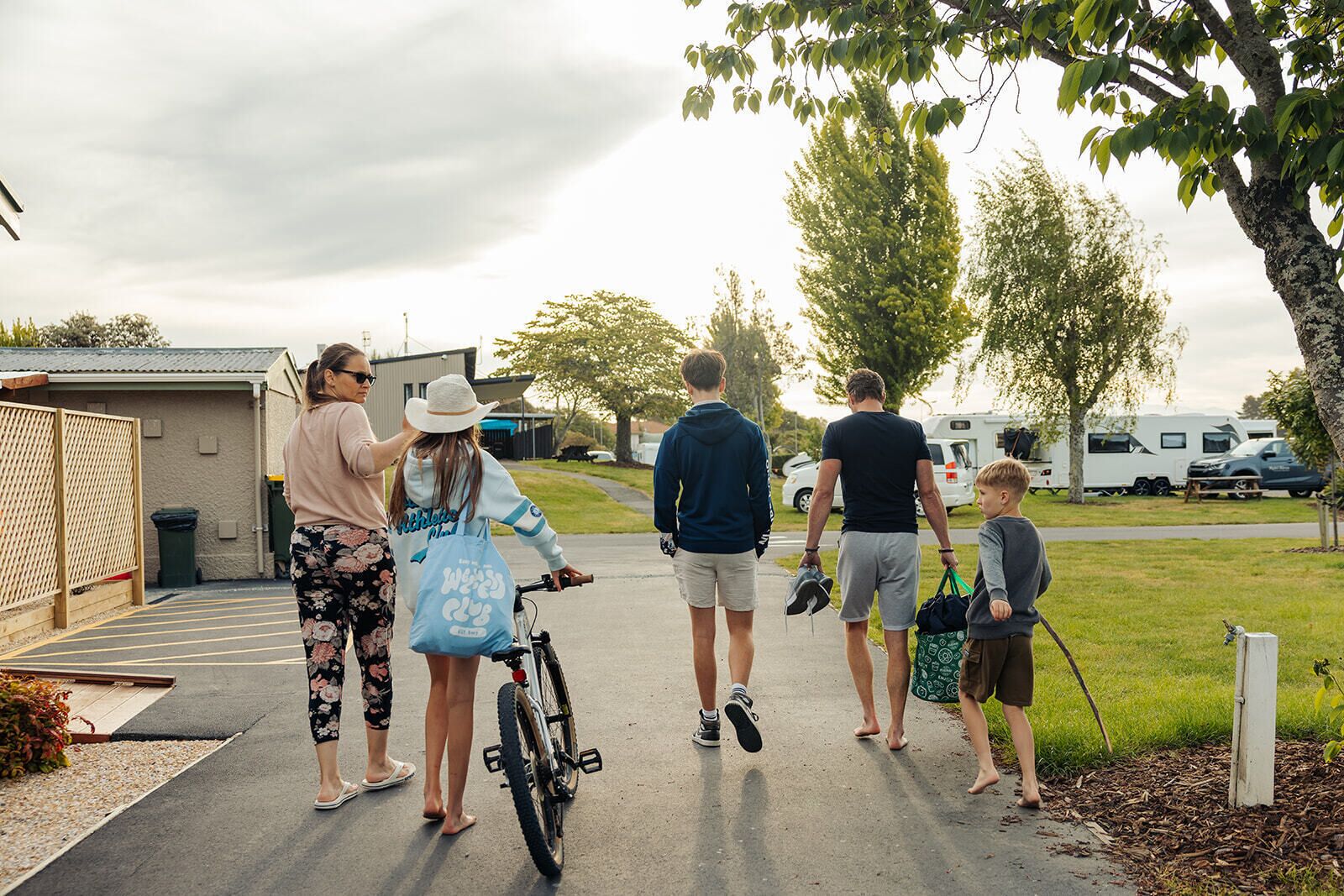 A family walking on a paved path in a campground with RVs in the background.