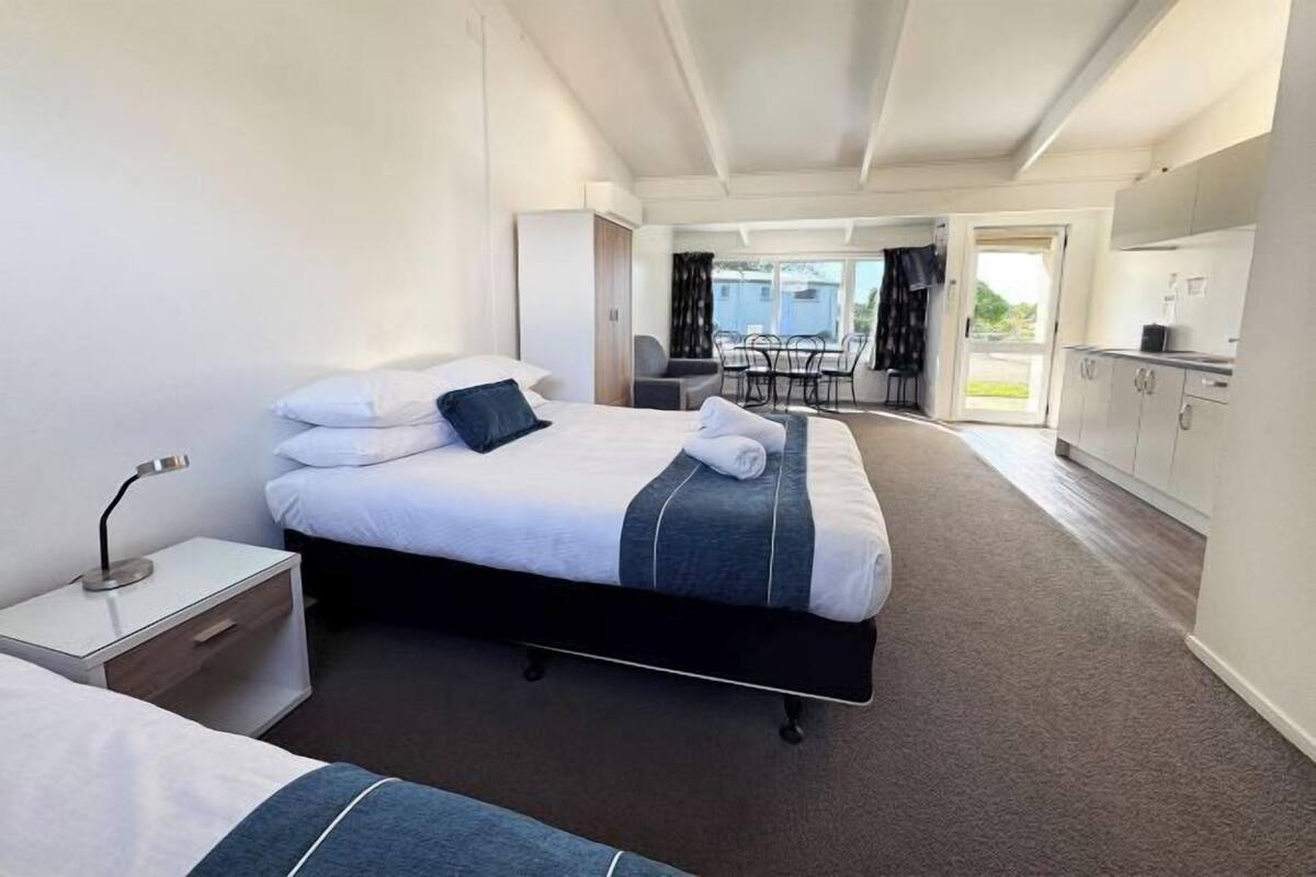 A hotel room with a bed, bedside table, and a view of the balcony.