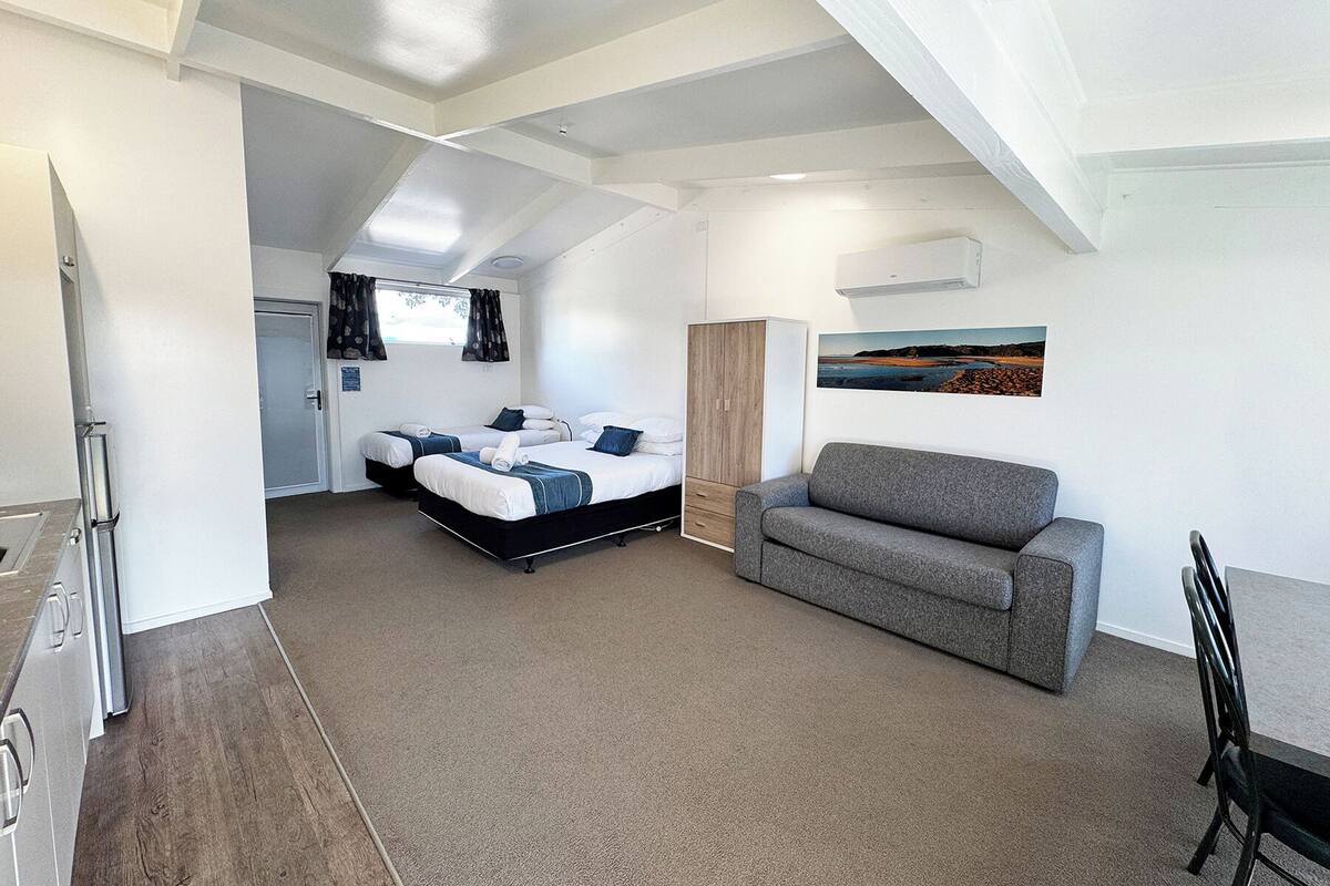 A compact room with a bed, a sofa, a small table, and a picture on the wall.