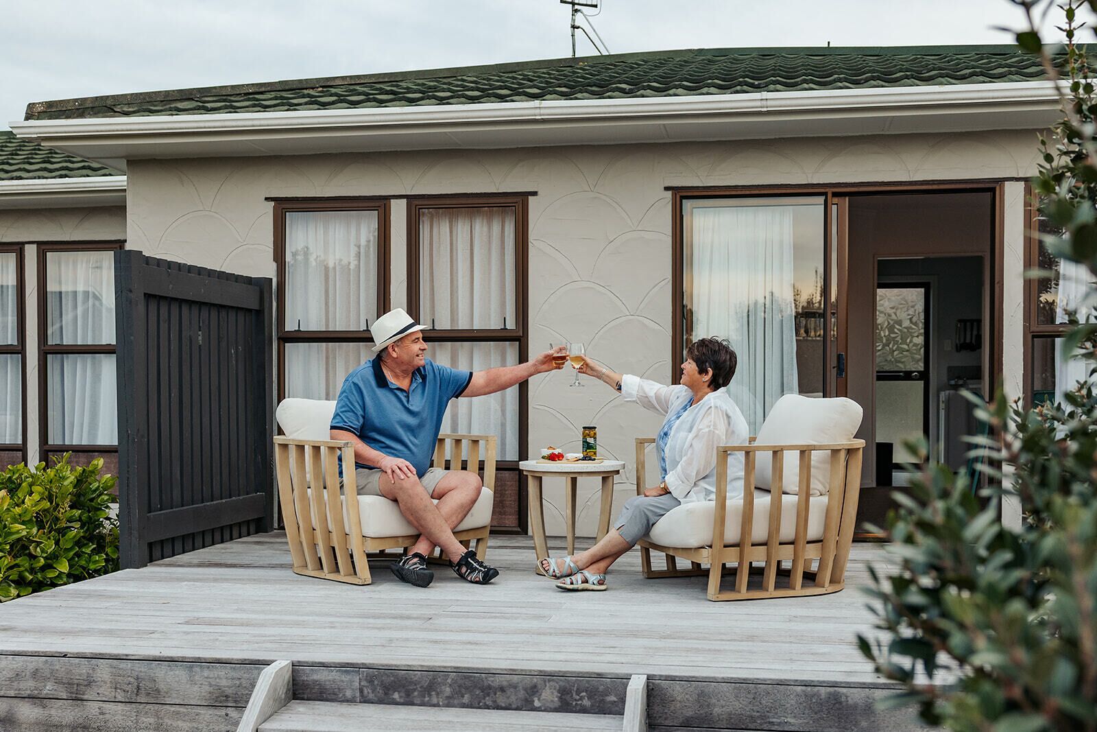 Two people seated on outdoor patio chairs facing each other, with a small table between them.