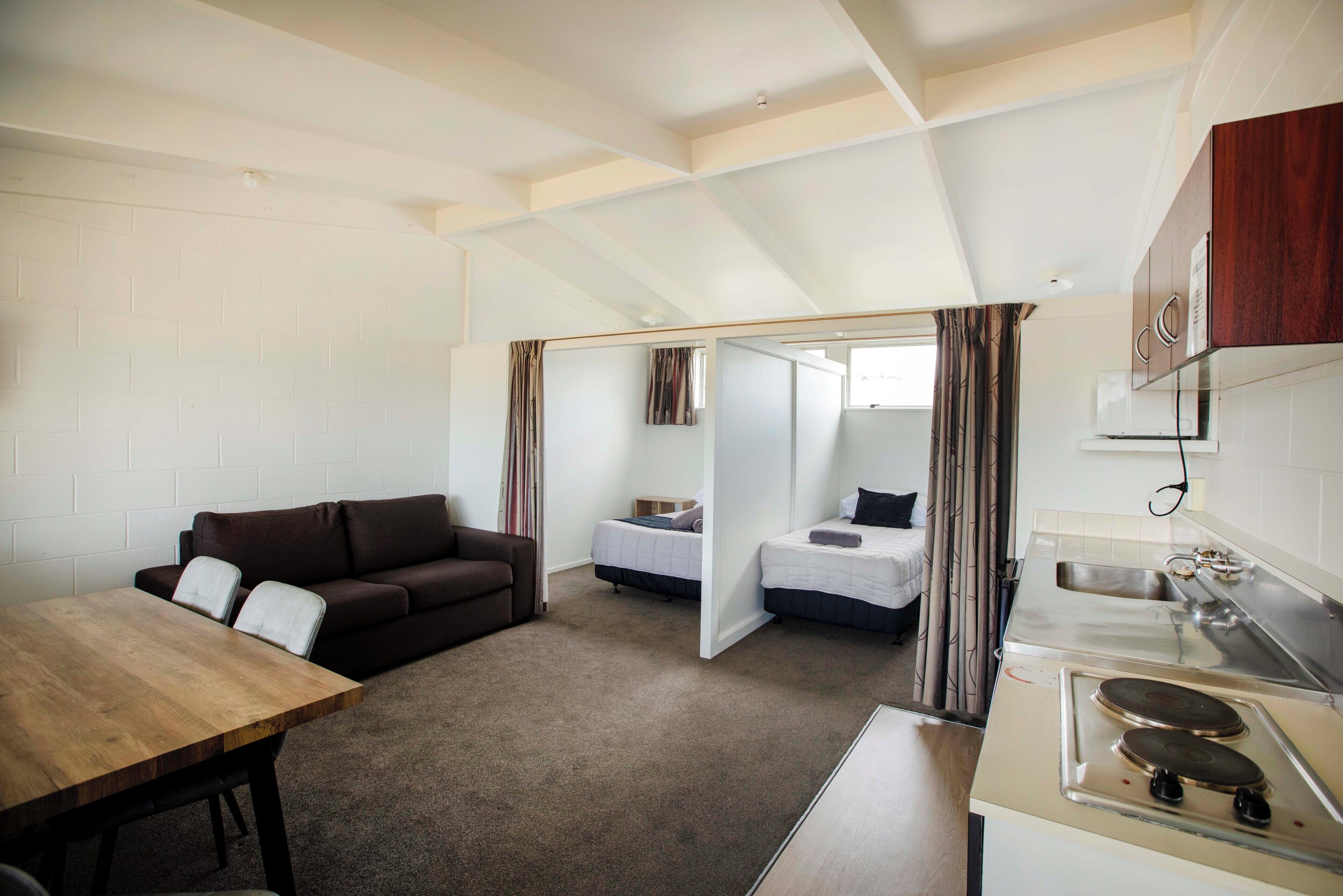 A compact living space with a kitchenette, a sofa, a dining table, and a bed.