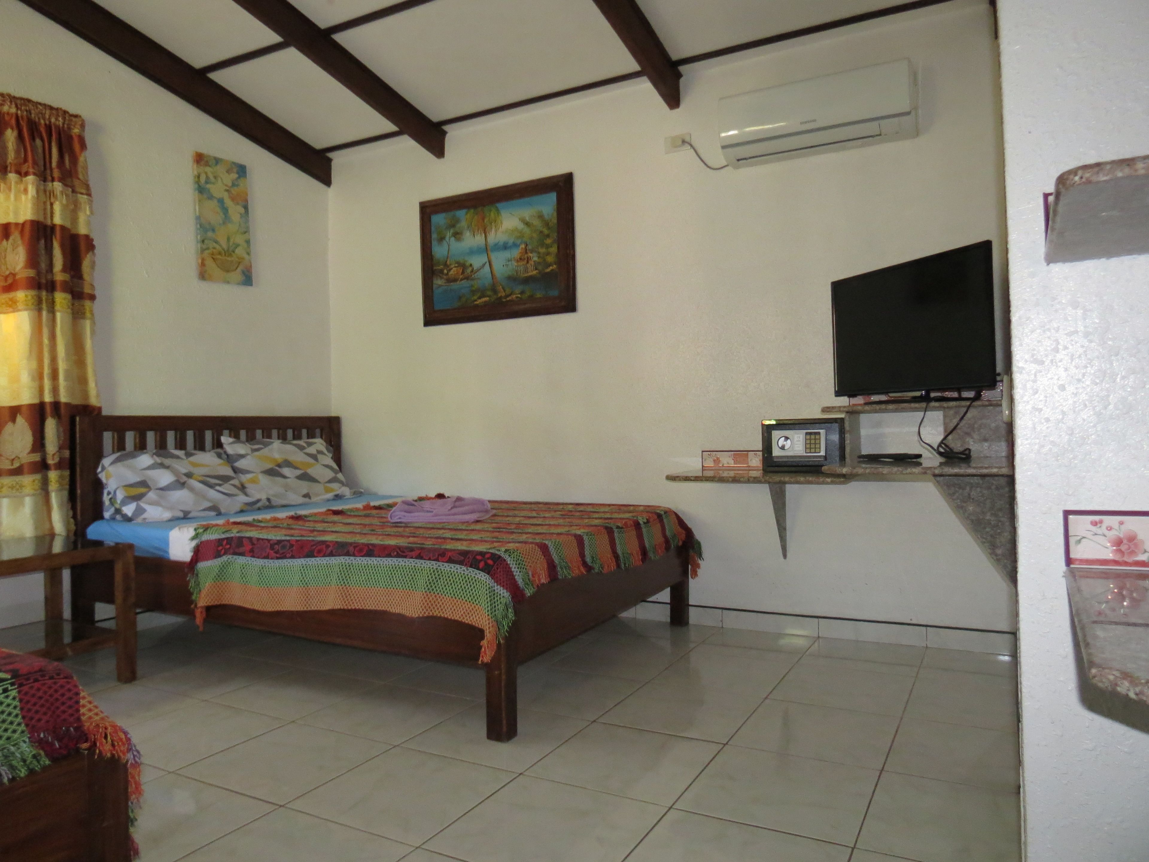 A bedroom with a bed, a TV, and a small shelf with a microwave.