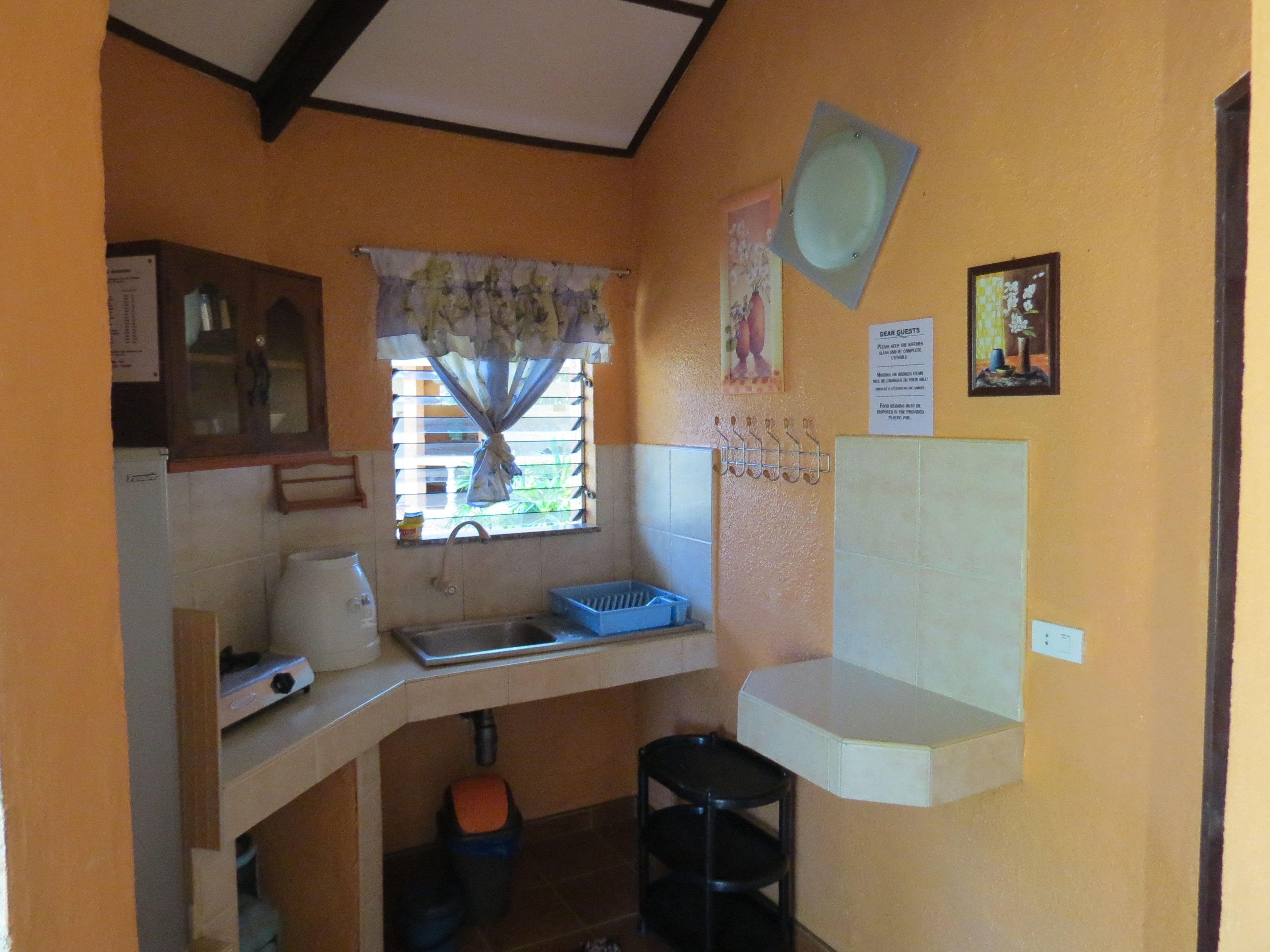 A compact kitchen with a window, a sink, a stove, and a small countertop.