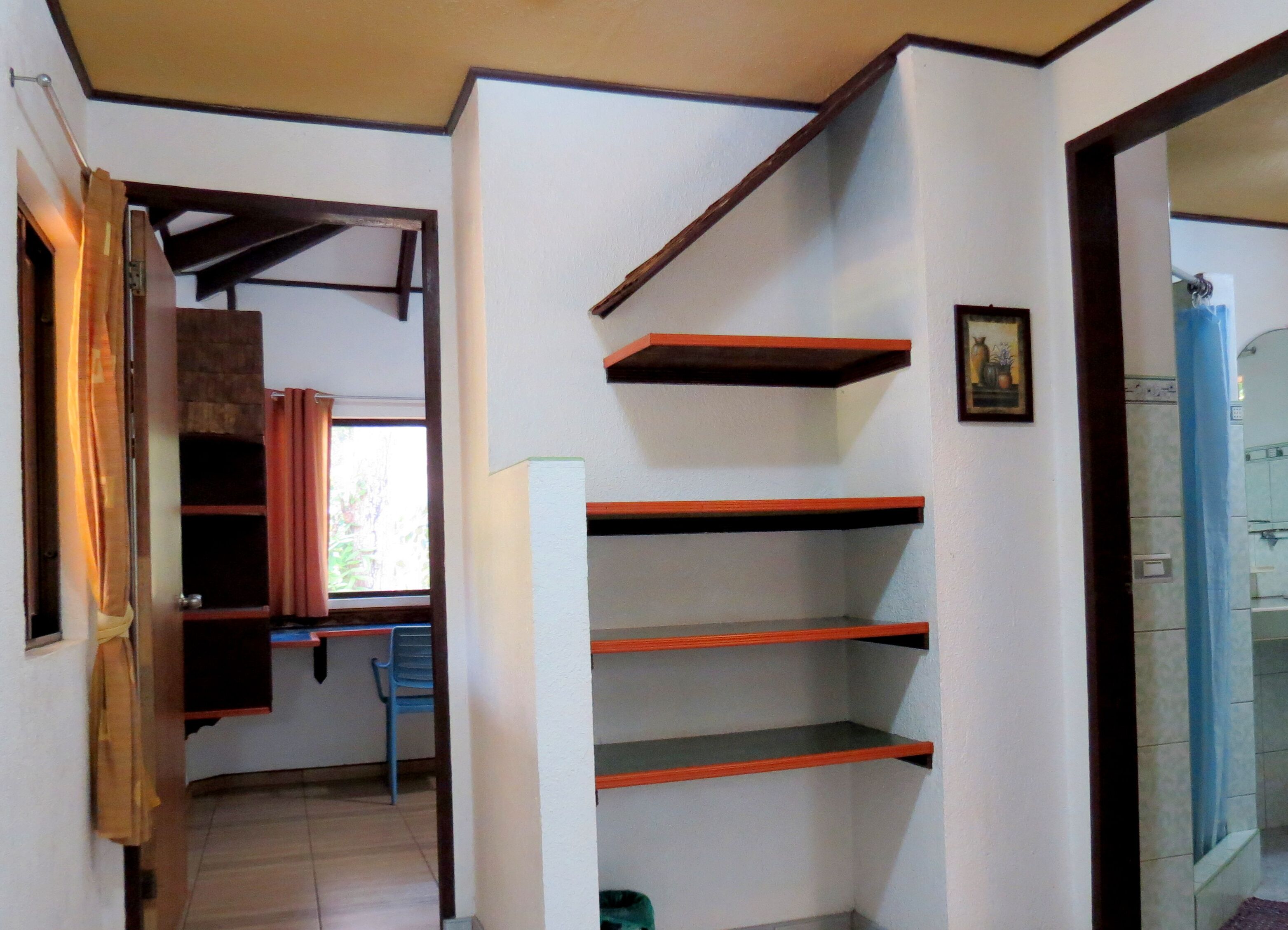 Una habitación con una escalera, una silla azul y una estantería.